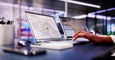 African American woman closely examining cadastral map on laptop screen in office - executive, cartographer, construction planning.
